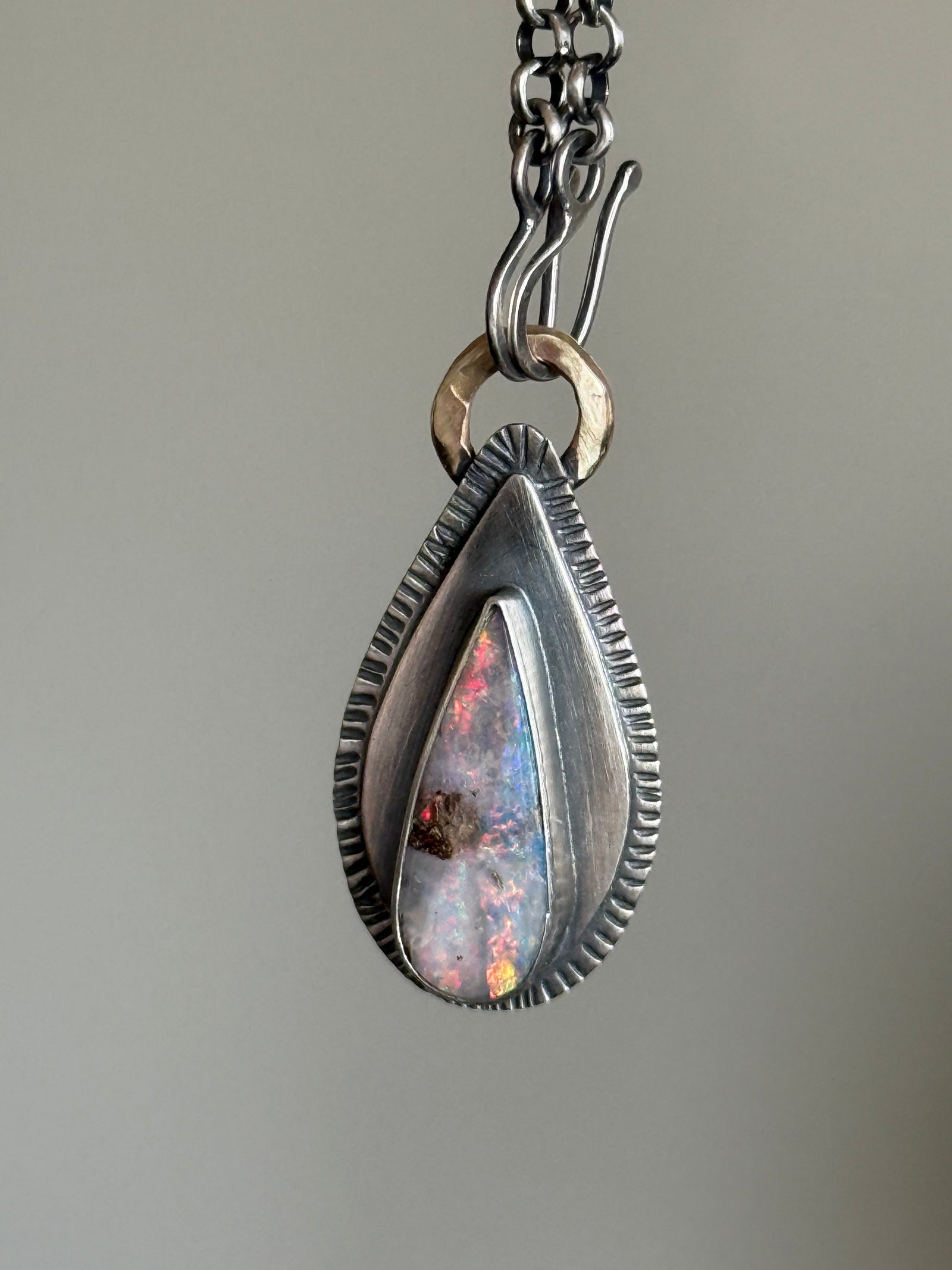 Teardrop boulder opal pendant with pink and violet colour play, set in sterling silver on a dark chain