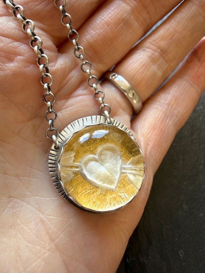Carved quartz heart pendant with 24k gold Keum Boo detail, held in a hand