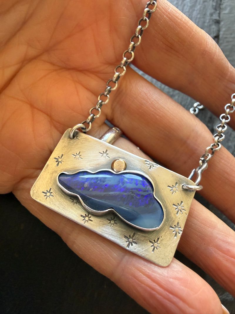 Deep blue cloud shaped opal pendant on a gold and silver mount