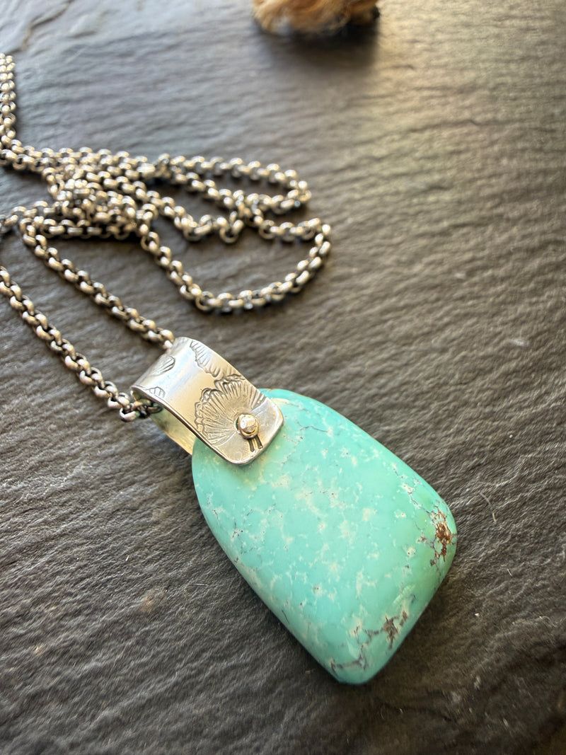 Chunky turquoise pendant with a flower stamped silver bail