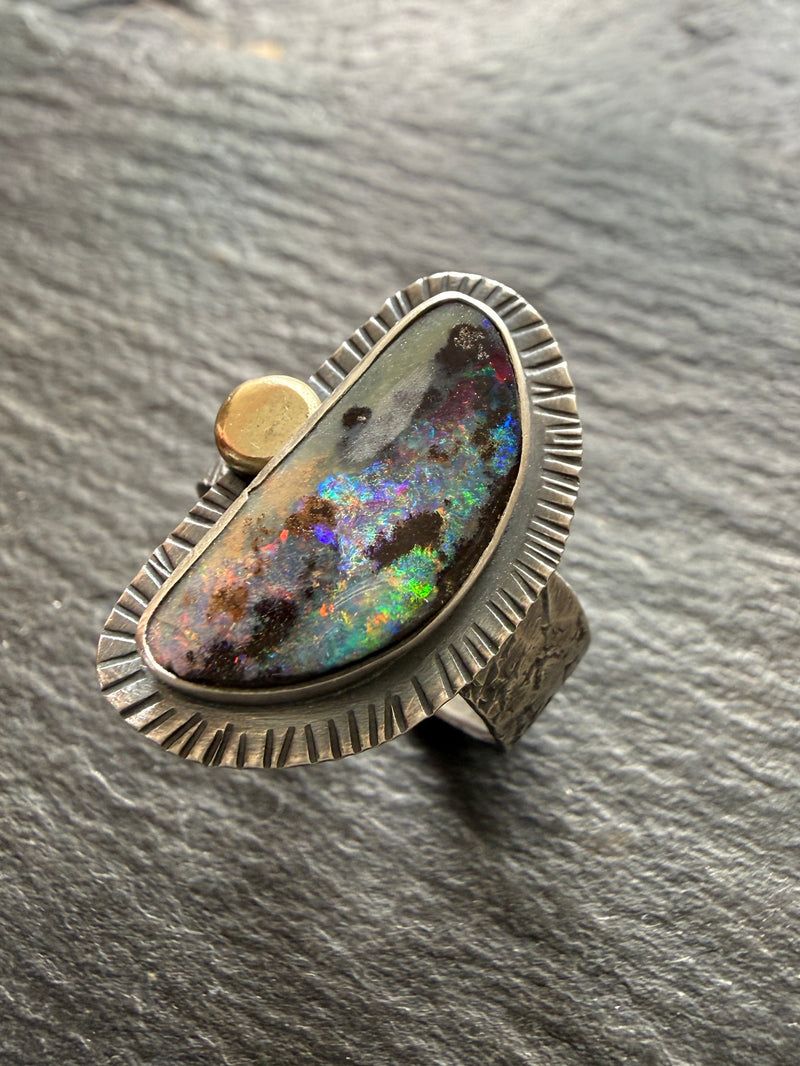 Boulder opal ring with violet colour play in a stamped silver bezel with gold accent